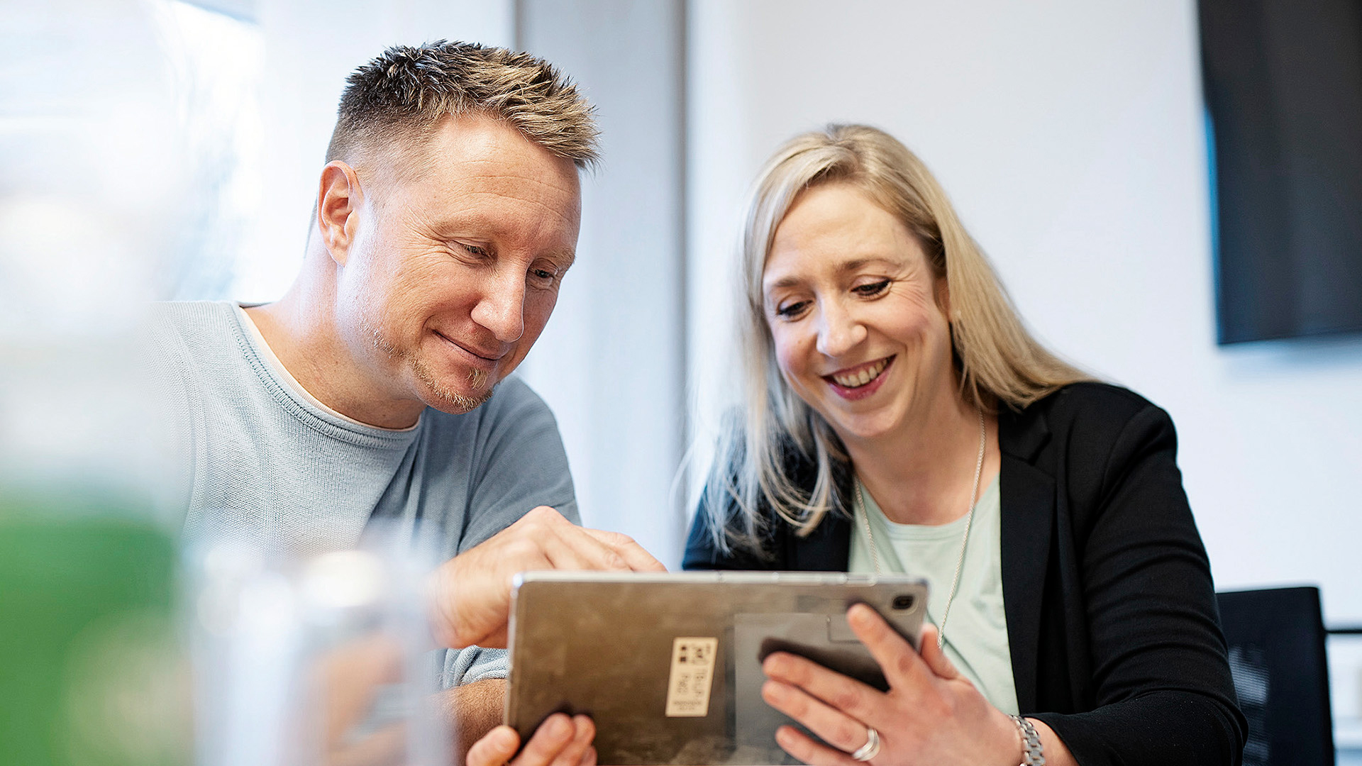 Bild zwei Mitarbeiter sitzen vor einem Tablet